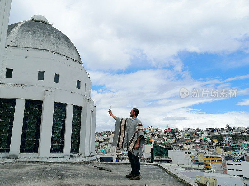 拉丁游客/摄影师在厄瓜多尔通古拉瓦的安巴托(Ambato)周围旅行，放松和享受旅程，同时用手机拍照到大教堂的圆顶;背面，城市景观在晴天多云的日子。